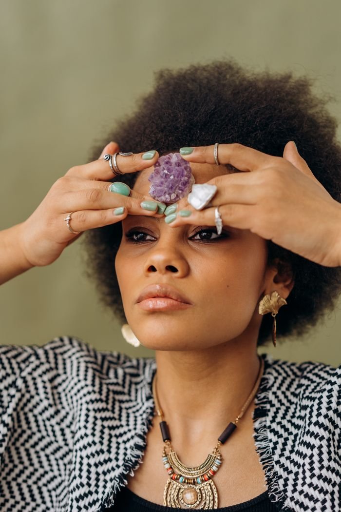 Portrait of a woman meditating with amethyst crystal, symbolizing harmony and spiritual energy.